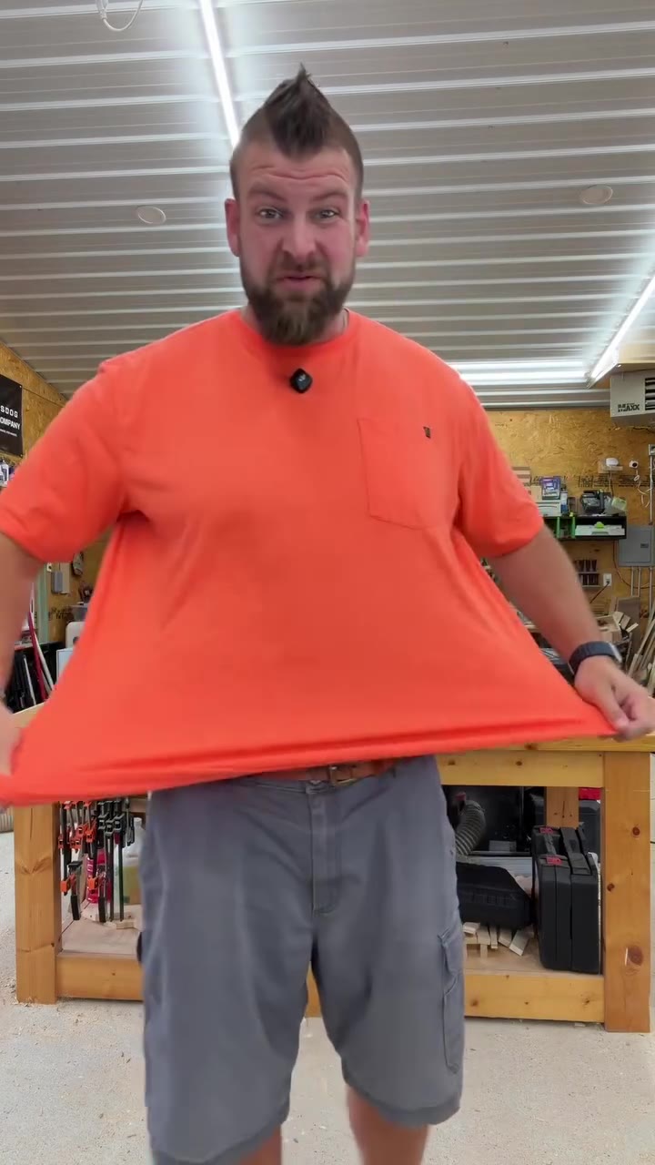 Bigger man holding a sized up orange standard tee out from his body